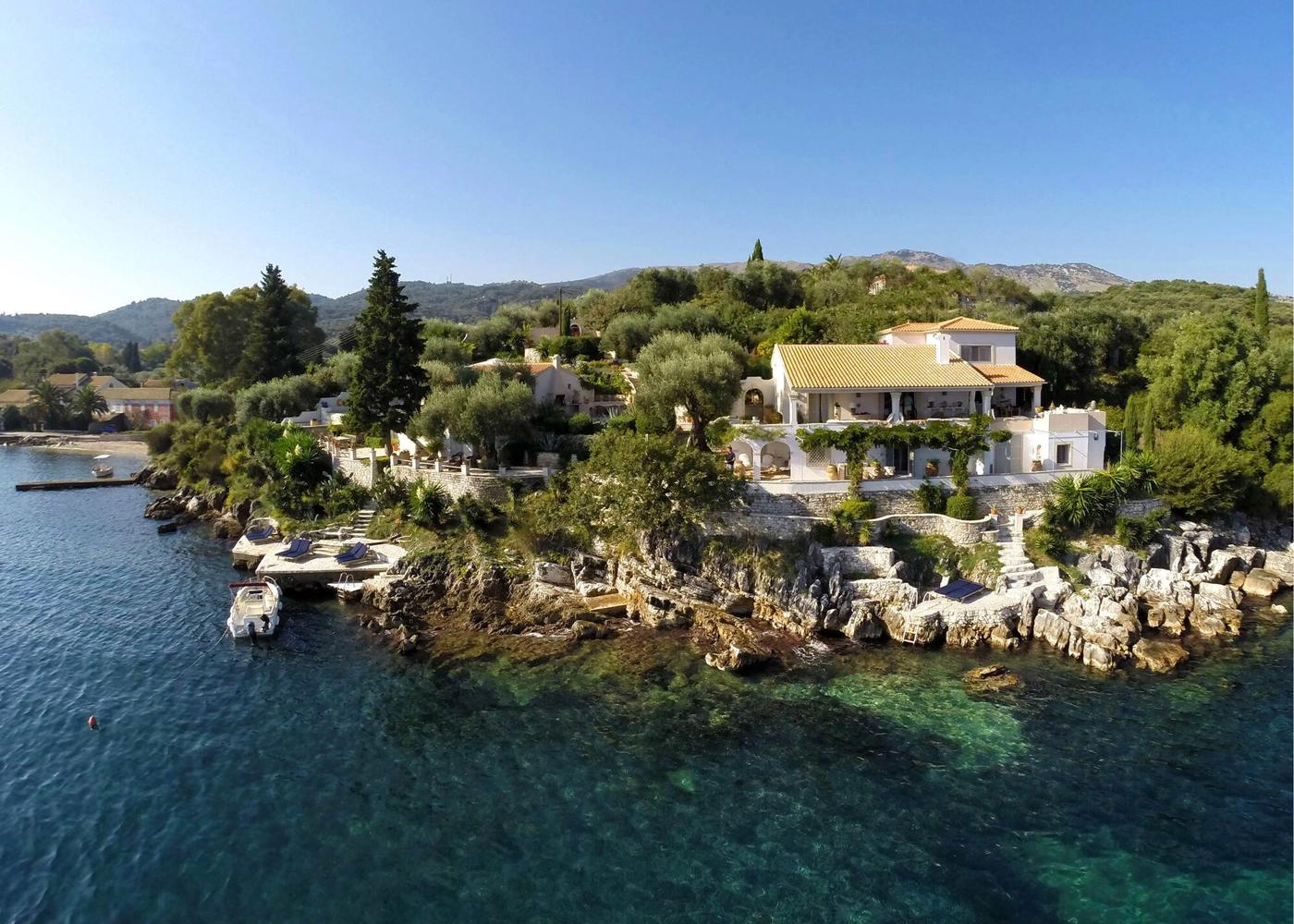 Villa Yeraki on its own rocky headland in Corfu, olive and cypress trees above clear turquoise water