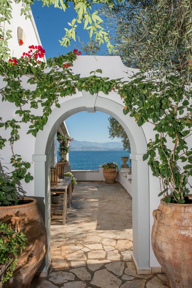 A whitewashed archway at Villa Yeraki hung with bougainvillea, opening onto a terrace above the sea