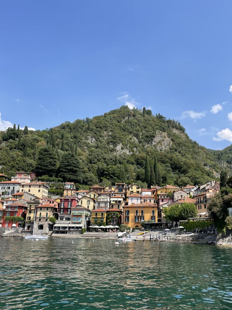 A pastel-coloured village on the shore of Lake Como, wooded hills rising behind it