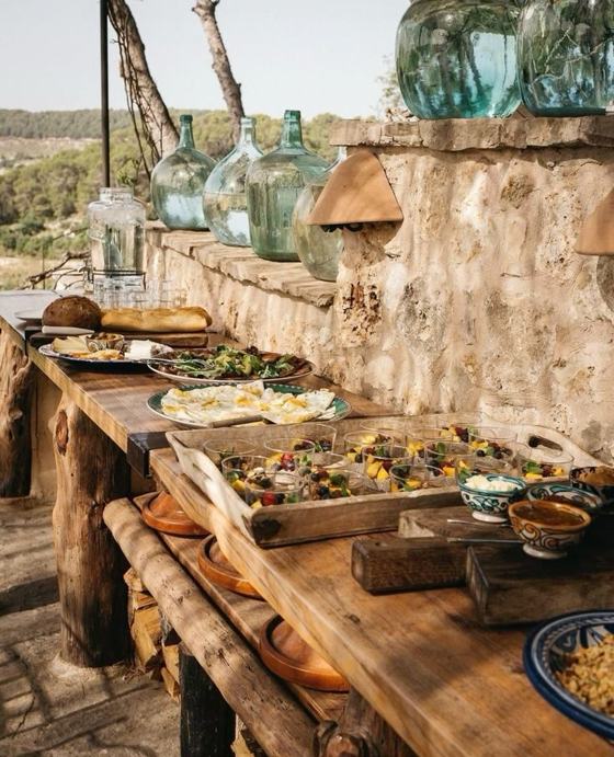 A rustic stone terrace laid with dishes for a long lunch