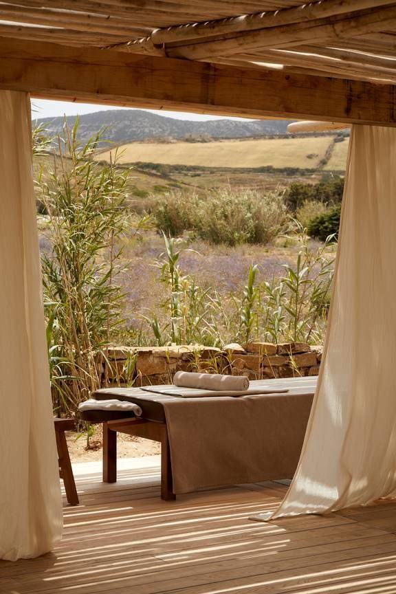 A massage table under a white curtained pergola, lavender fields beyond