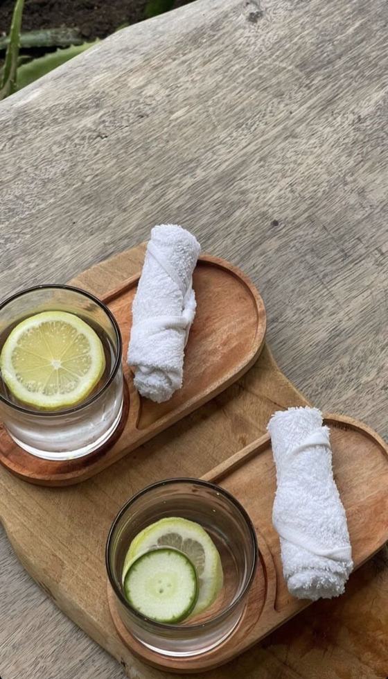 Glasses of water with lemon and cucumber beside rolled white towels