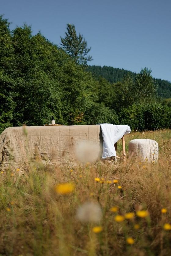 A daybed dressed in white linen in a meadow of wildflowers
