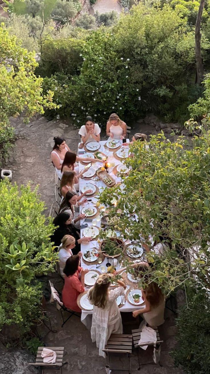 A long table in a garden, with many women dining together