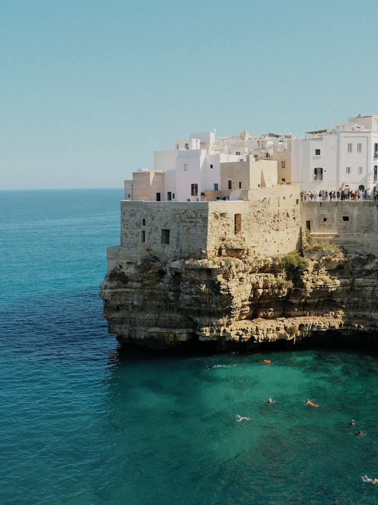 A whitewashed Puglian town on its limestone cliff above clear turquoise water