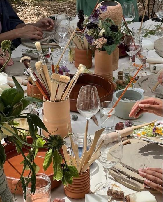 Brushes, clay pots and flowers on a long table during an artisan workshop