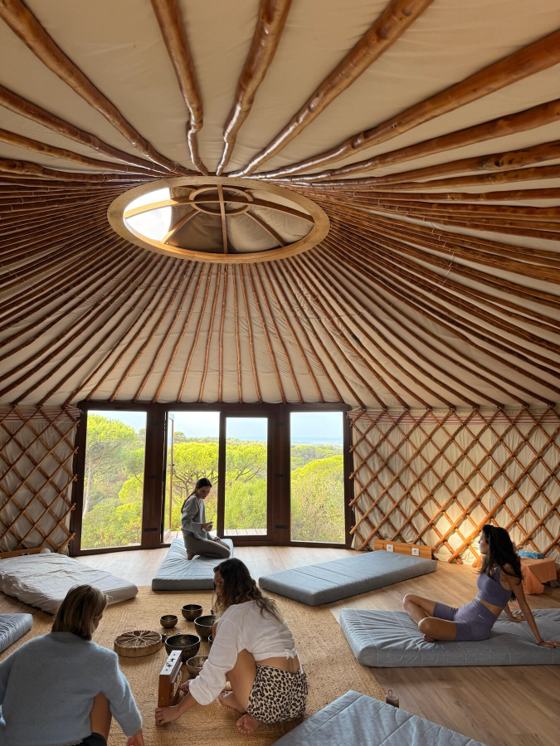 A morning class on mats inside a sunlit yurt